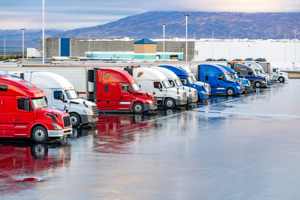 A truck parking lot, 
filled with multiple trucks,
after the rain,